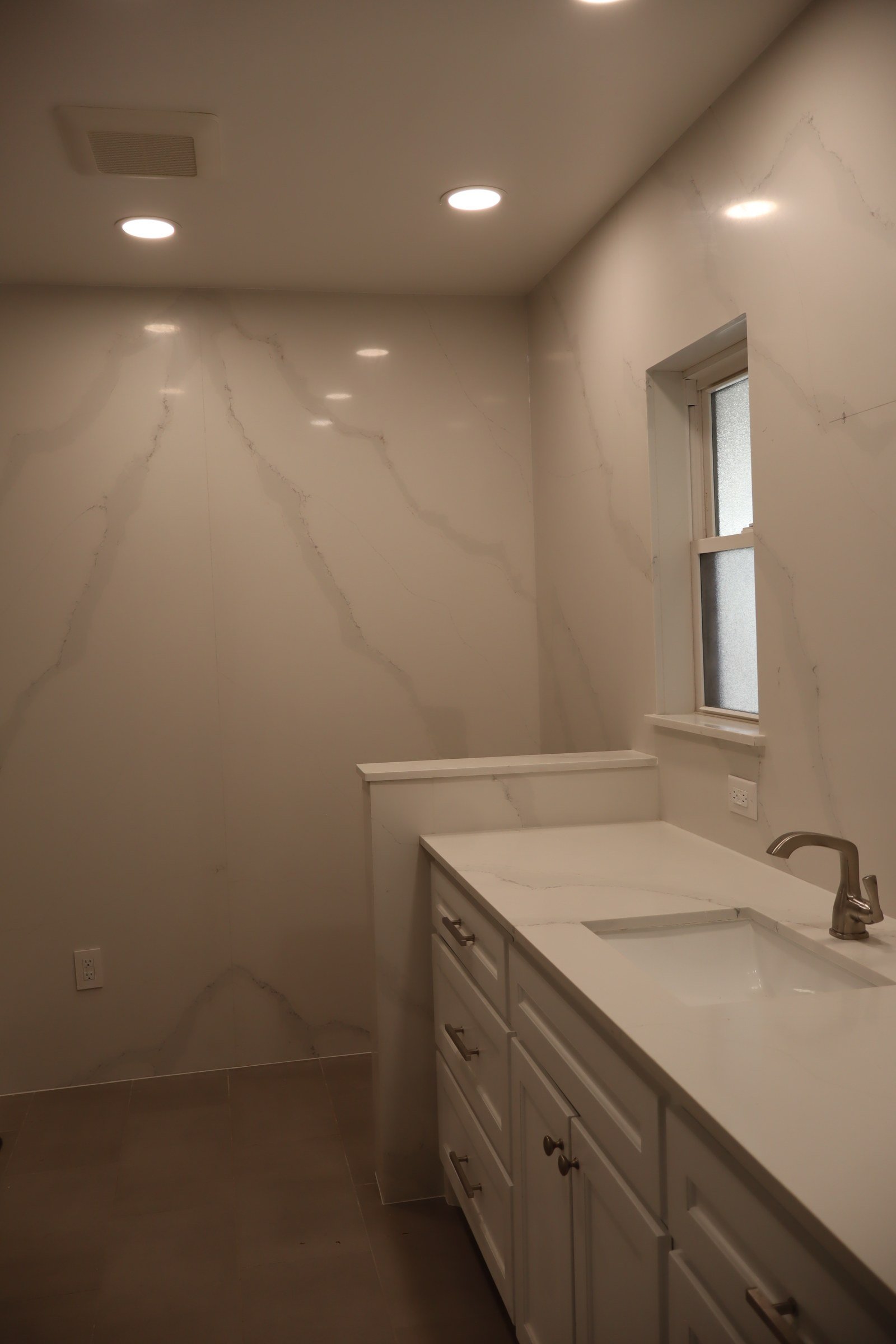 Baño con encimera y pared en cuarzo blanco veteado por Torres Granite